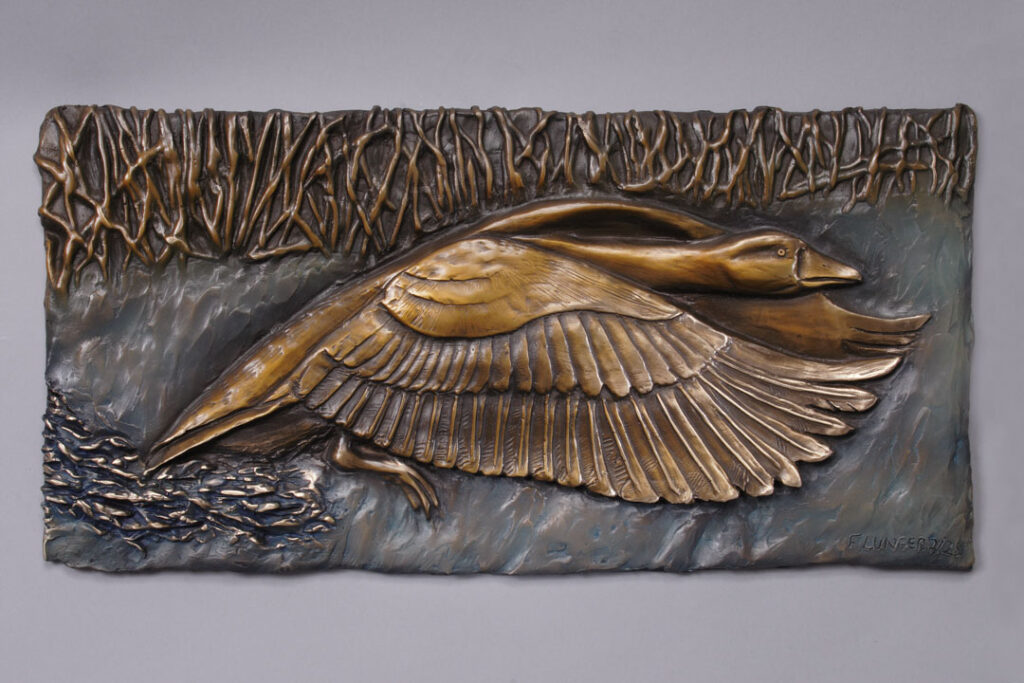 A bronze relief of a Goose taking flight