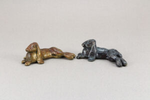 Two little flop eared rabbit sculptures. One is patina'd brown and white, and the other black and white.