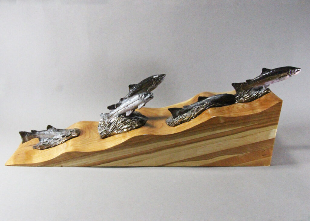 Bronze Salmon migrating upstream, where the water is represented by carved cherry wood.
